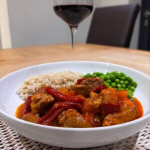 Paprika Pork served with brown rice, peas and a glass of red wine