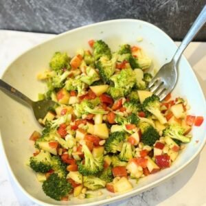 Truly Yummy Broccoli Salad in a serving bowl with salad servers.