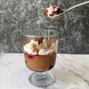 A single serving of Truly Yummy Chocolate Mousse layered with pitted black cherries and whipped cream.