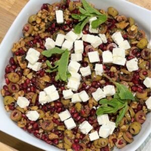 Finished bowl of Truly Yummy Baked Rice topped with a salsa of fresh mint, green olives, walnuts and pomegranate seeds dressed in a garlic, pomegranate molasses and olive oil dressing