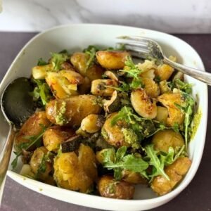 A bowl full of roasted jersey royal potatoes, courgette and capers dressed in fresh pesto and tossed in wild rocket leaves