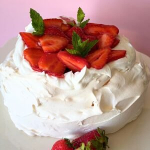 Truly Yummy Strawberry Pavlova, crisp meringue, freshly whipped plant-based cream and sliced strawberries garnished with mint