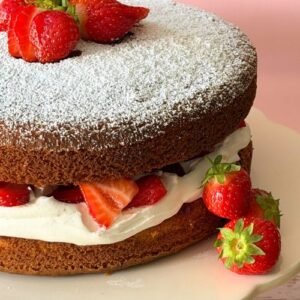 Gluten free and dairy free Victoria sponge cake filled with freshly whipped plant-based cream, strawberry jam and fresh strawberries