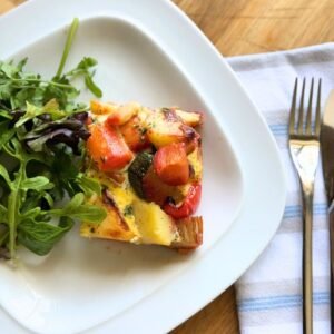 A slice of Truly Yummy Vegetable Frittata with a green salad on the side